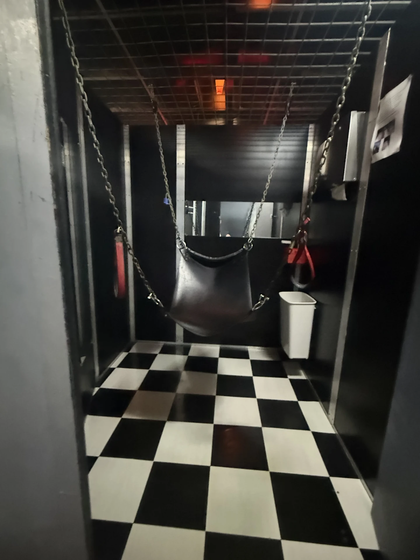 Private sling room at Cruise Club Cairns with a chain-hung leather sling above chequered tiled flooring