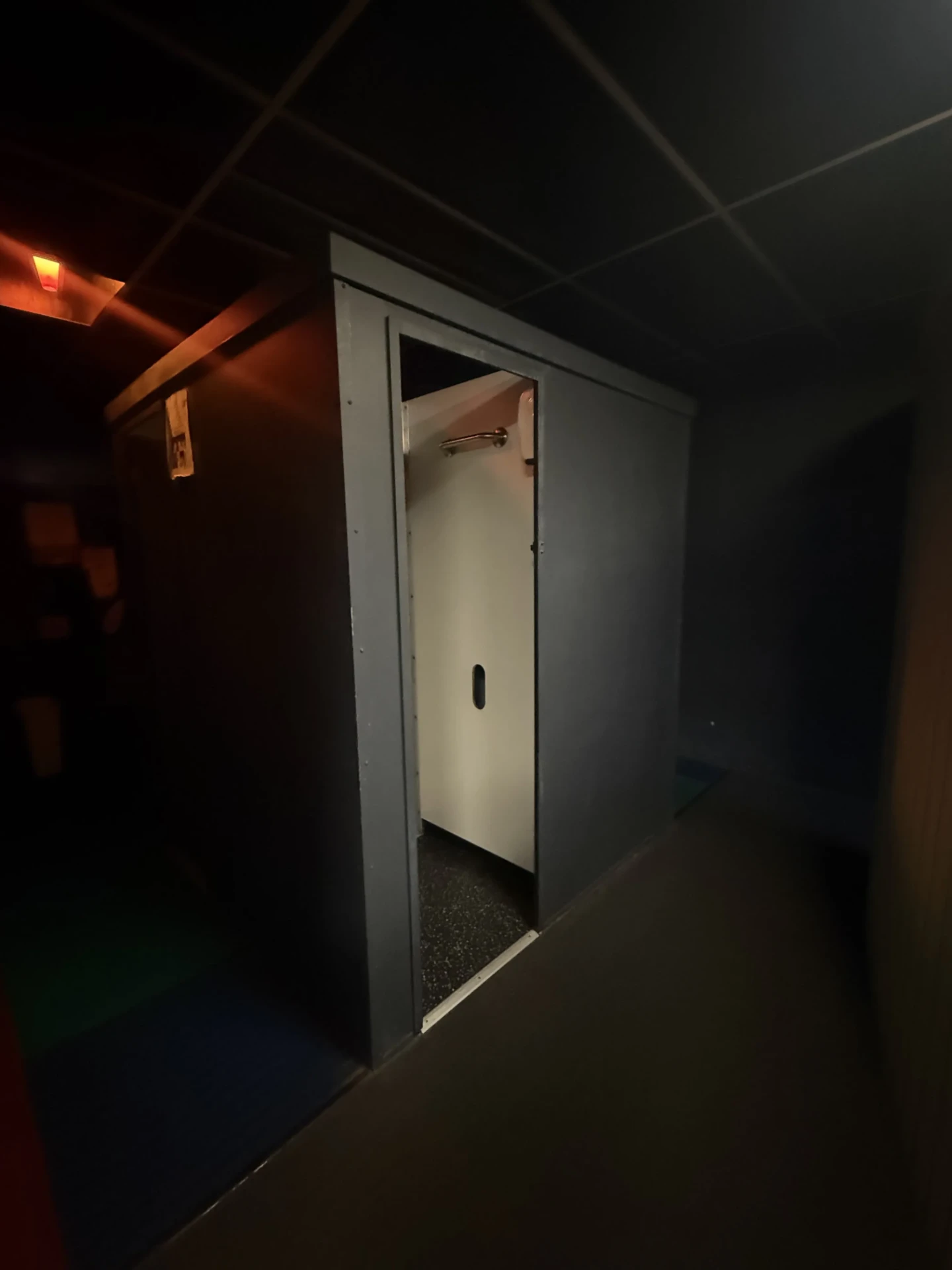 Darkened corridor at Cruise Club Cairns with an open private room door and a warm amber ceiling light